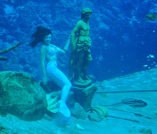 Photo of an underwater mermaid with a statue